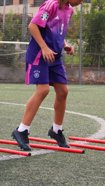Jugadora saltando entre picas rojas en un ejercicio de coordinación y agilidad