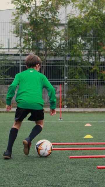 Niño regateando entre conos durante un entrenamiento de tecnificación de fútbol 11 en Madrid